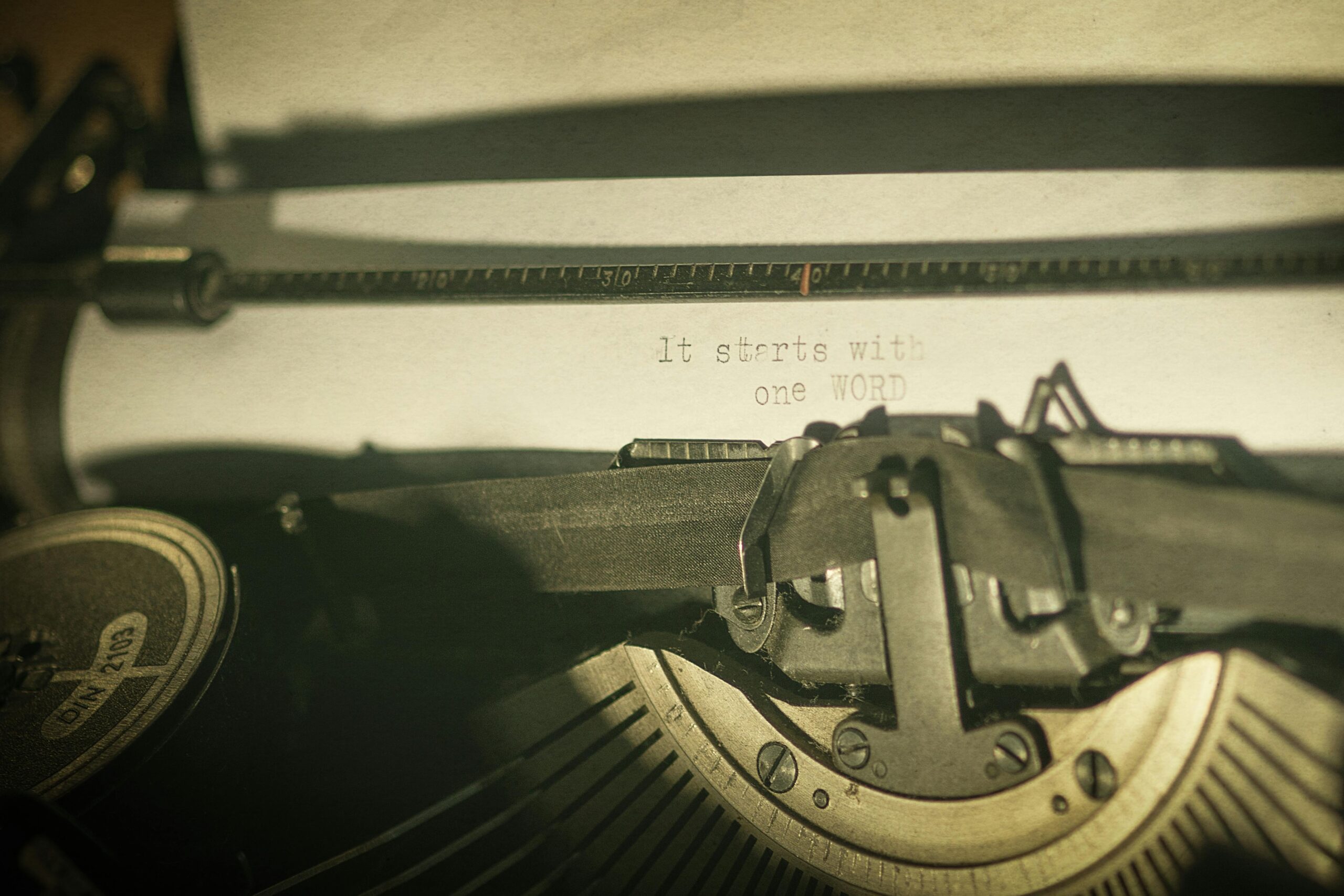 Close-up of a vintage typewriter with a typed message 'It starts with one word,' symbolizing creativity and writing inspiration.